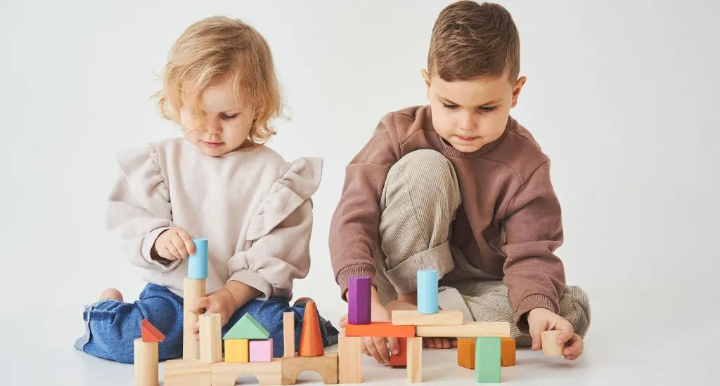 Zwei Kinder spielen nebeneinander mit Holzspielzeug und Plastikspielzeug im direkten Vergleich
