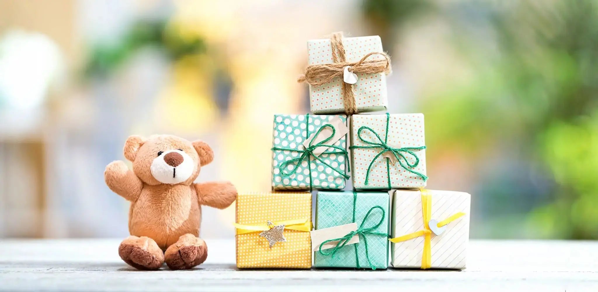 Kleiner Teddybär neben mehreren bunt verpackten Geschenken, symbolisch für kreative und altersgerechte Geschenkideen für Kinder